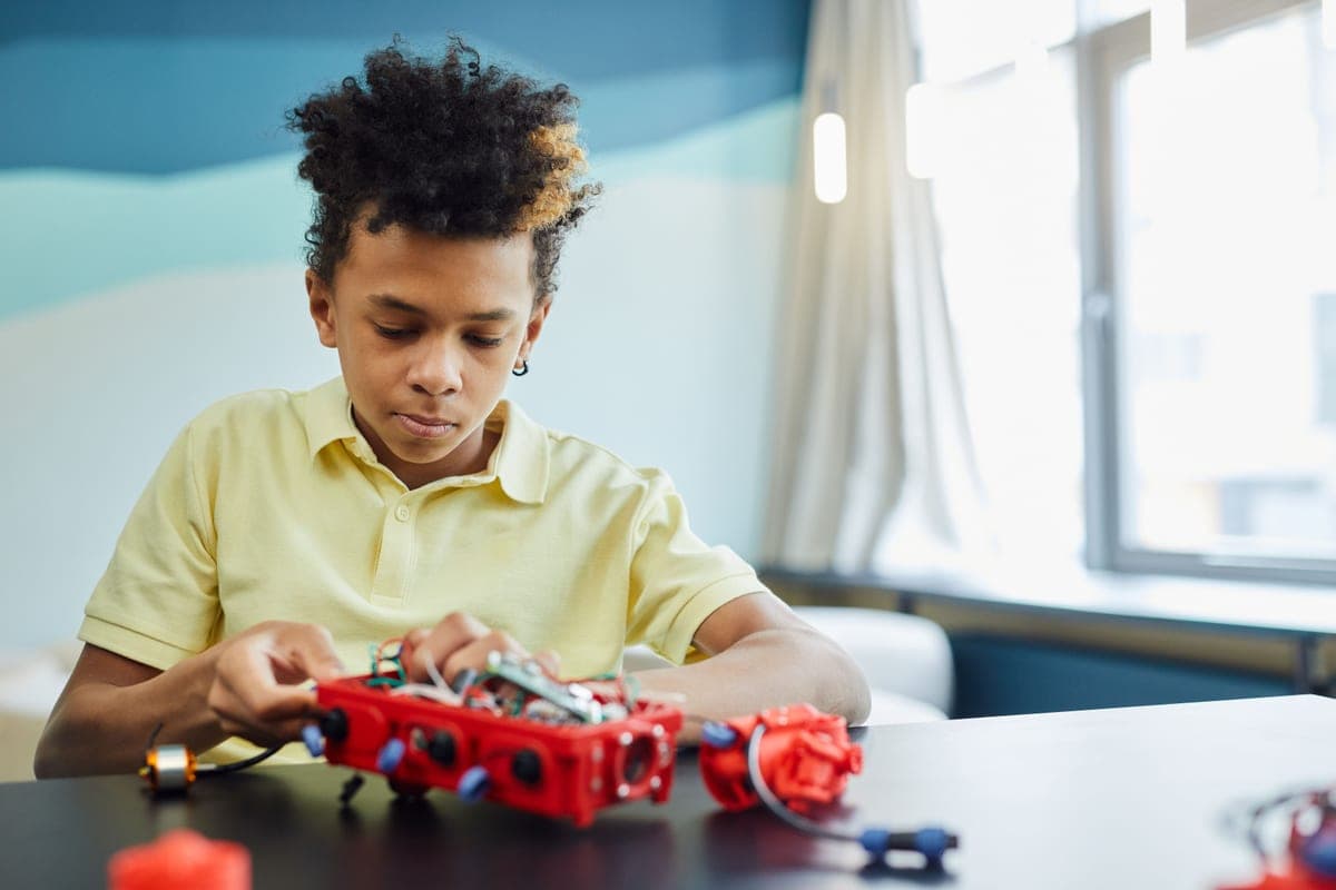 A child building a machine with gears and axles