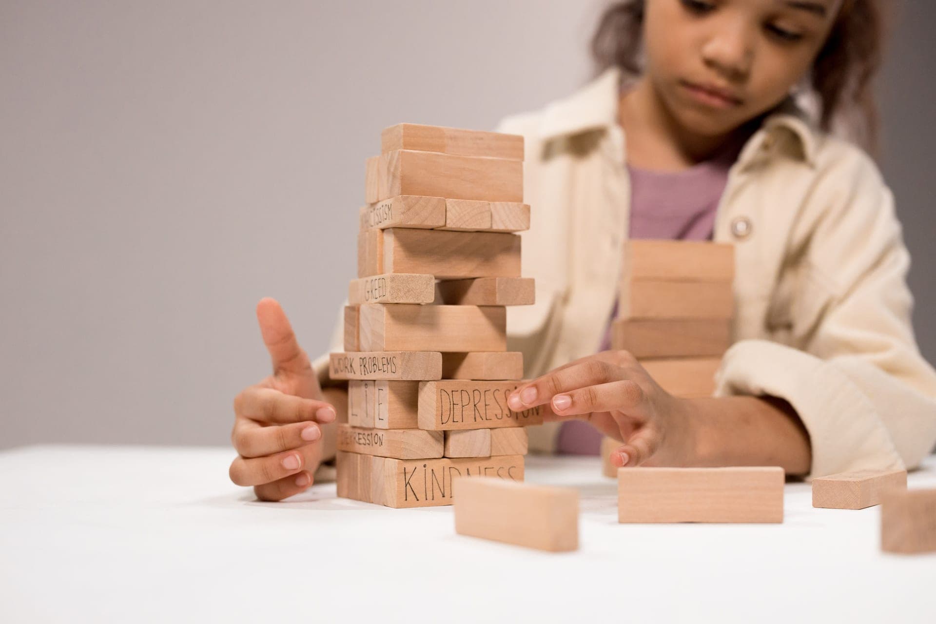 A child balancing a tall tower of identical wooden planks
