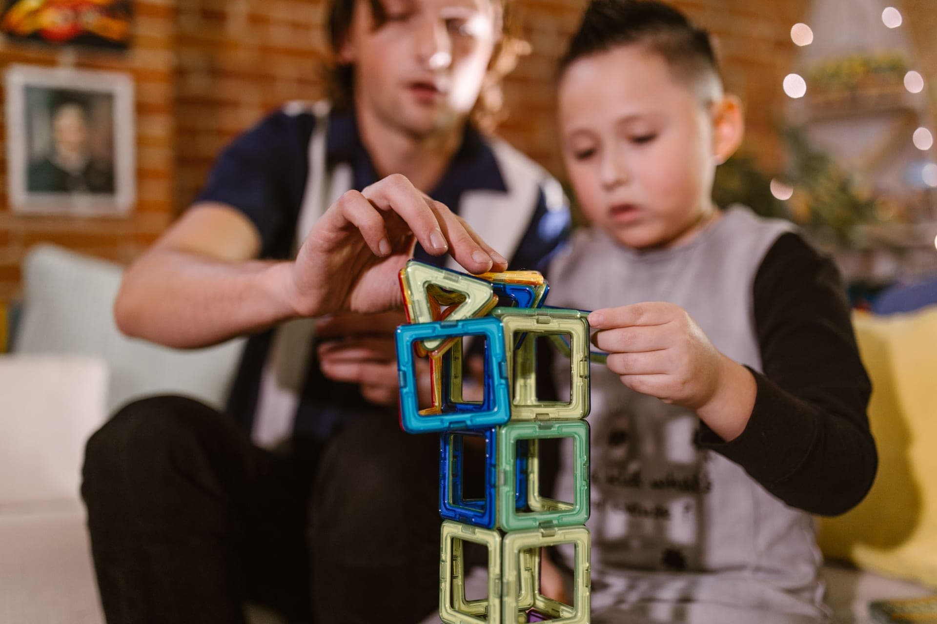 A child building a structure from colorful magnetic tiles