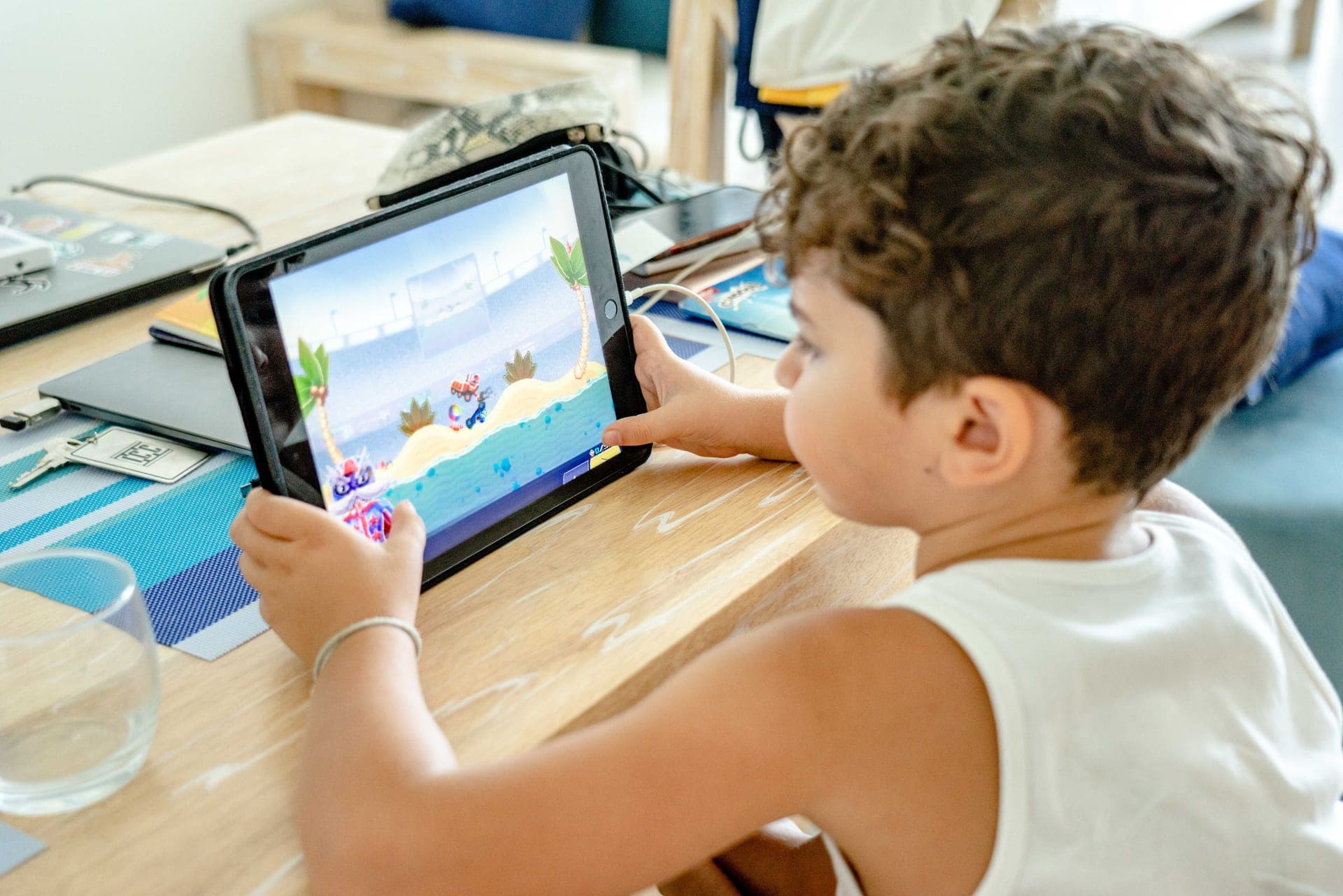 A child using a tablet-based learning game at a table