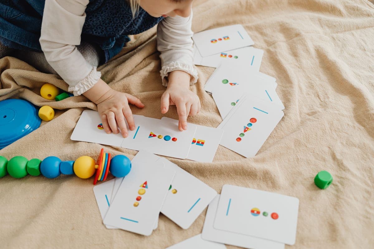A preschool child sorting colorful shapes into patterns
