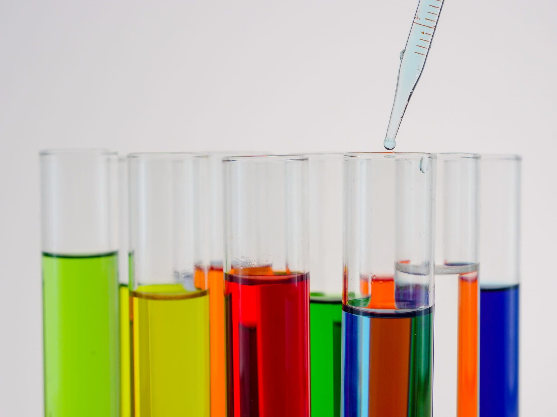 Colorful liquid in test tubes with a pipette