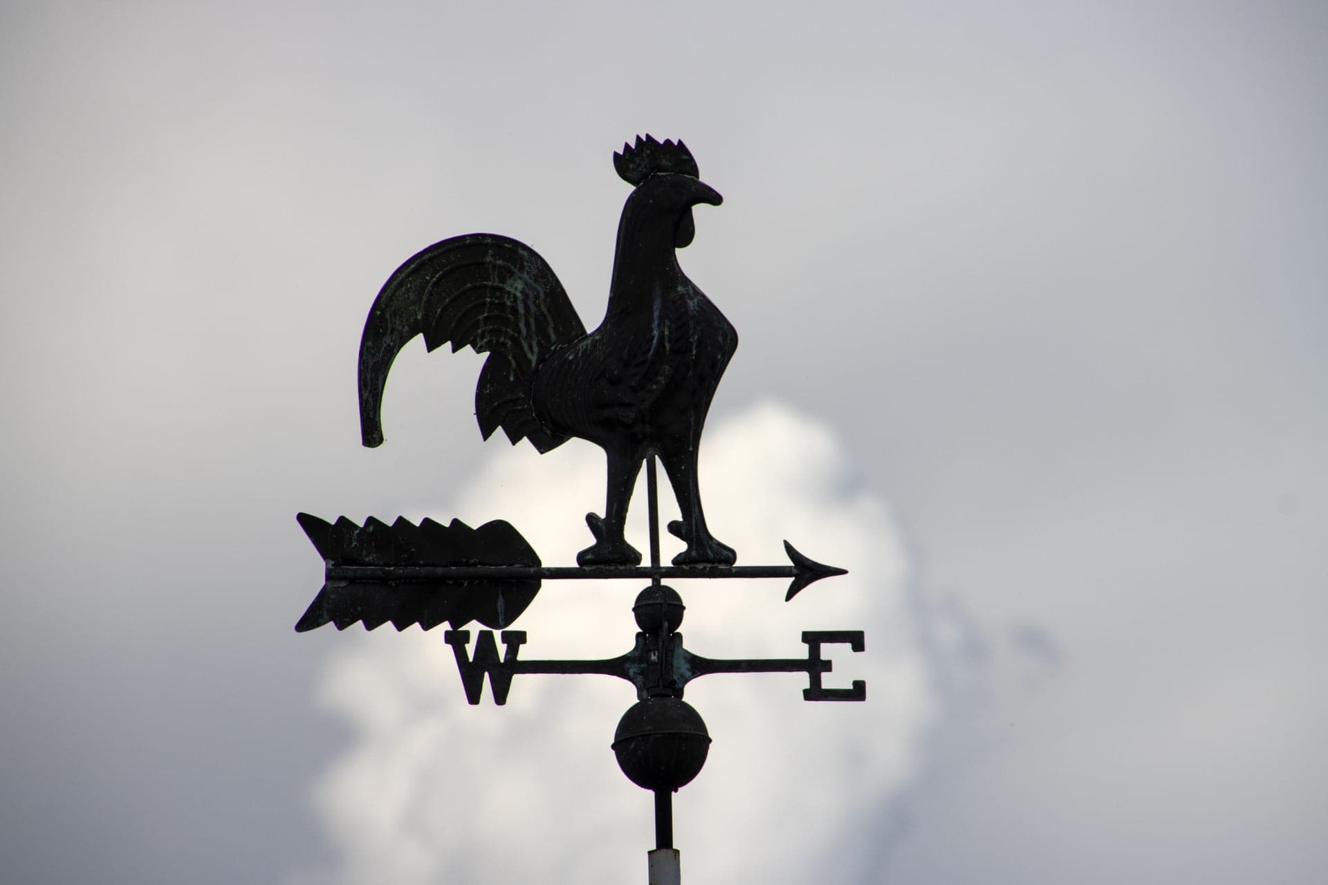 A weather vane against a cloudy sky