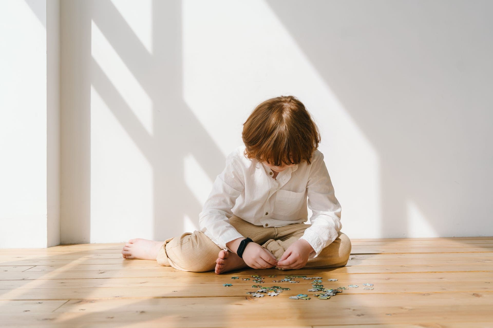 A child concentrating on a puzzle alone at a table