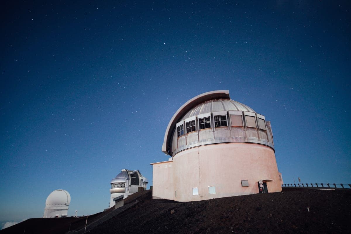 A telescope silhouetted against a starry night sky
