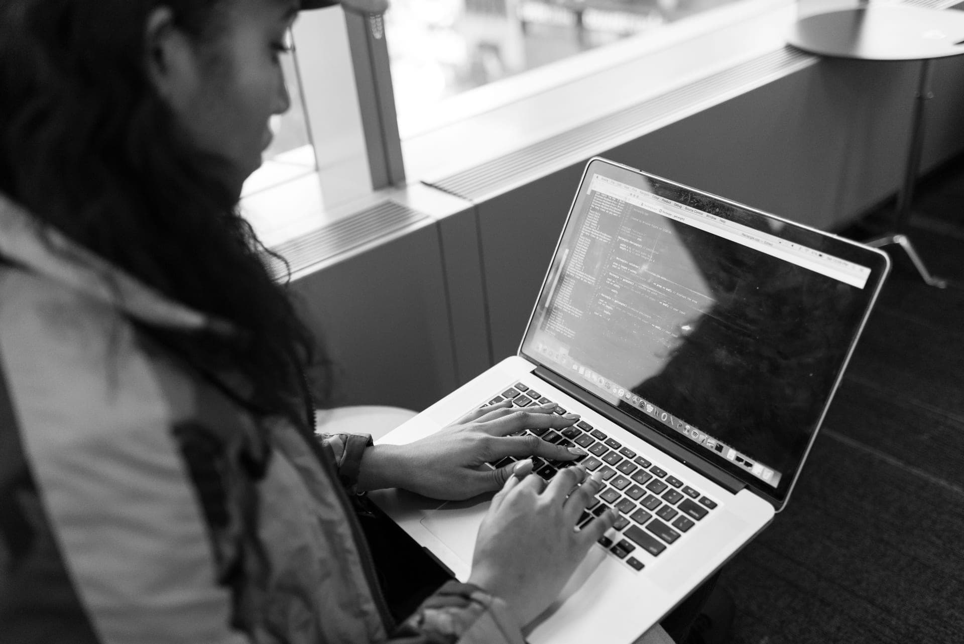 A child typing code on a laptop keyboard